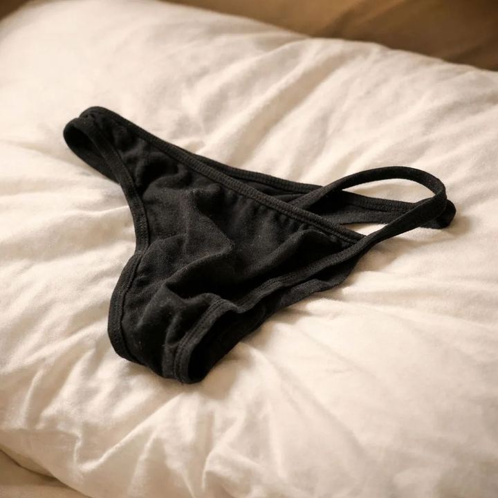 String noir en coton porté, posé sur un lit