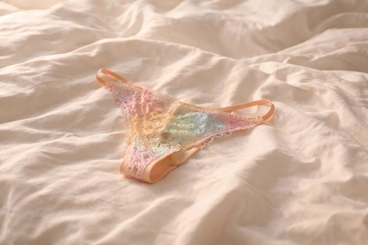 String en dentelle pastel porté, posé sur un drap